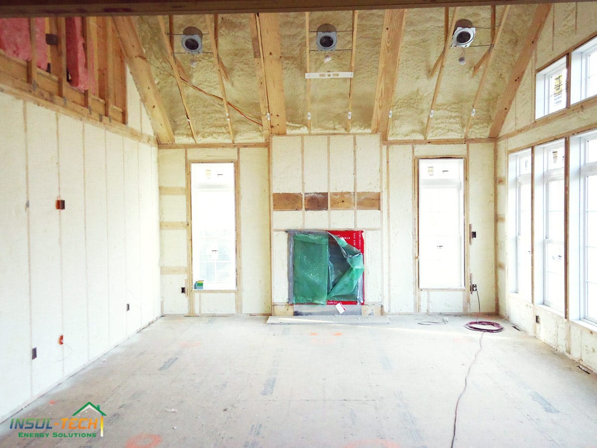 A room with spray foam installed in the ceiling and walls around wooden beams