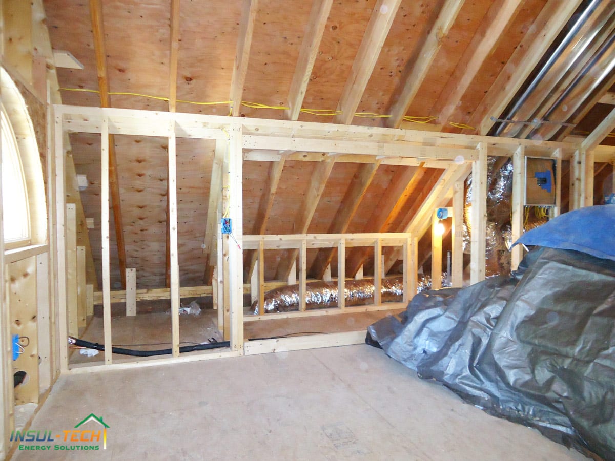 A close up of an empty room with wooden beams and angled ceiling