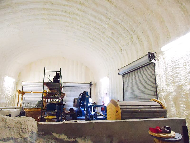 The inside of a large domed commercial building with spray foam on the inside of the roof and arched walls